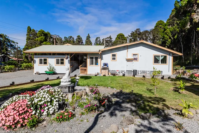 a view of a white house with a big yard and potted plants