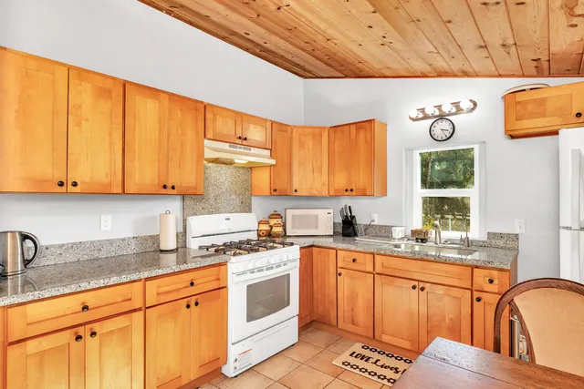 a kitchen with granite countertop a white stove top oven sink and cabinets