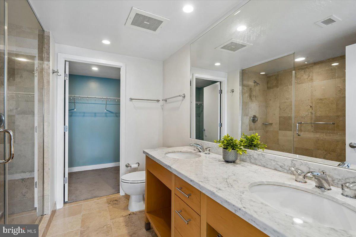 912 F Street Northwest, Unit 709 Washington, DC 20004 - Photo 15 of 28 a bathroom with a granite countertop sink a toilet a mirror and shower