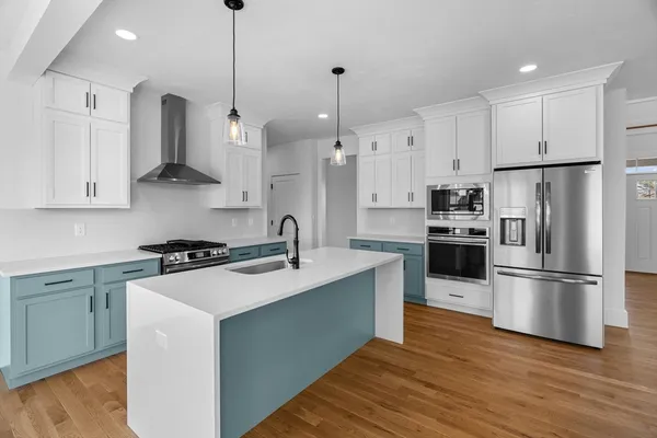 a kitchen with stainless steel appliances granite countertop a sink a stove a refrigerator and island with wooden floor