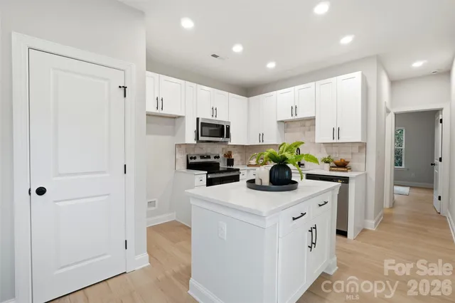 a kitchen with white cabinets and refrigerator