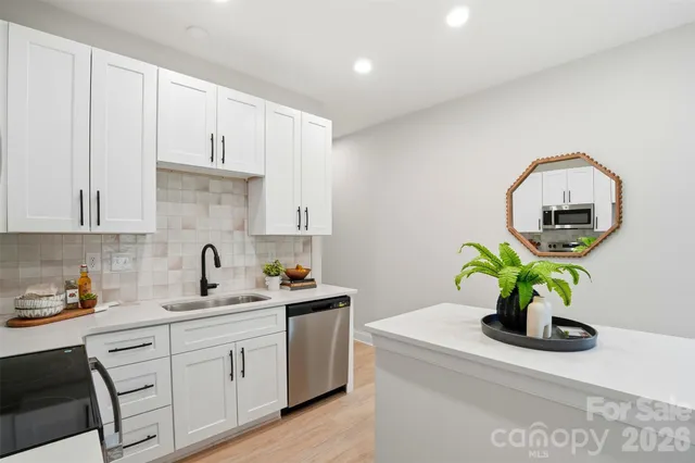 a kitchen with stainless steel appliances a sink a white counter space and a window