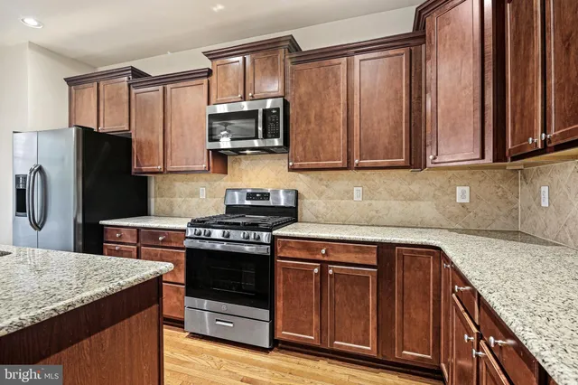 a kitchen with stainless steel appliances granite countertop a stove a sink dishwasher a refrigerator and a microwave oven