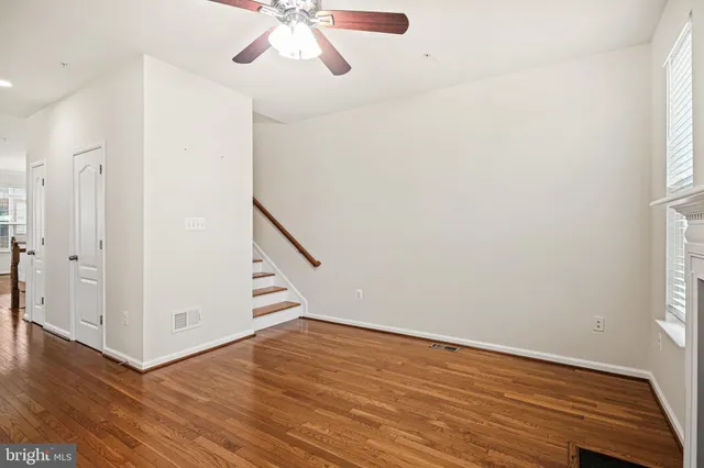 an empty room with wooden floor fan and windows