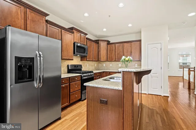 a kitchen with stainless steel appliances granite countertop a refrigerator a stove top oven a sink and dishwasher