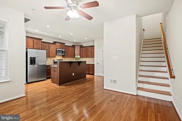a kitchen with stainless steel appliances a refrigerator and a wooden floor