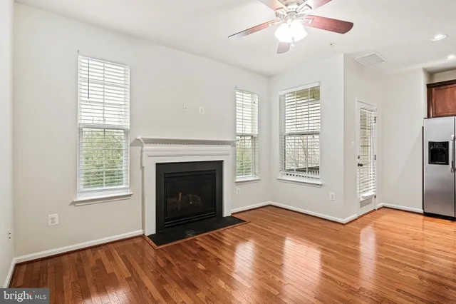 a view of an empty room with wooden floor fireplace and a window