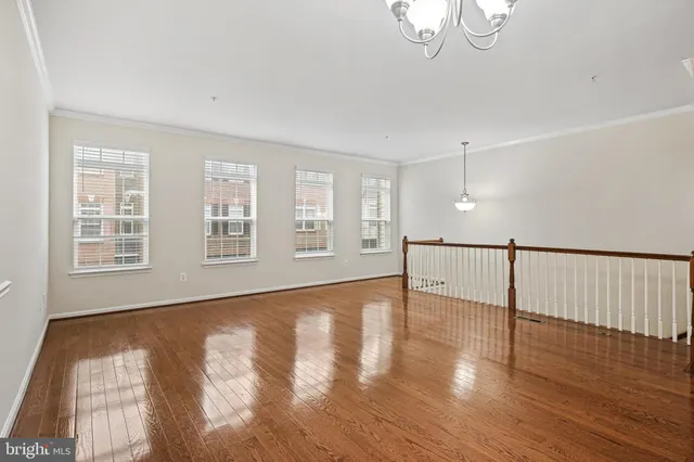 a view of an empty room with wooden floor and windows