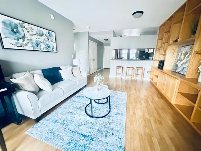 a living room with furniture a rug and kitchen view