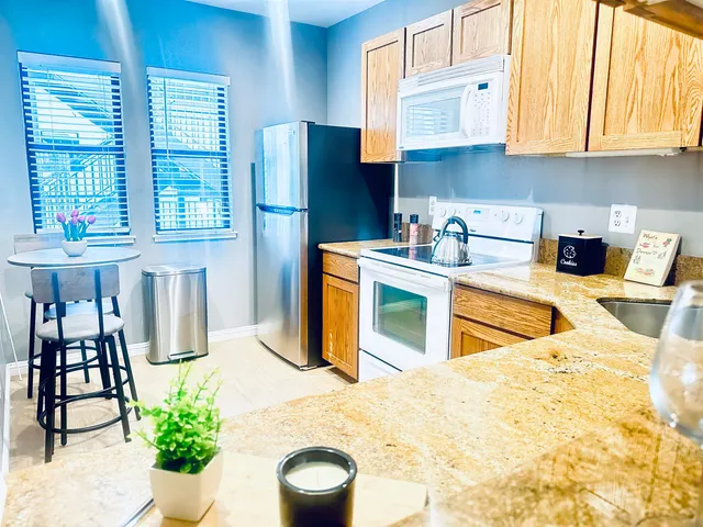 a kitchen with stainless steel appliances kitchen island granite countertop a refrigerator and a stove top oven