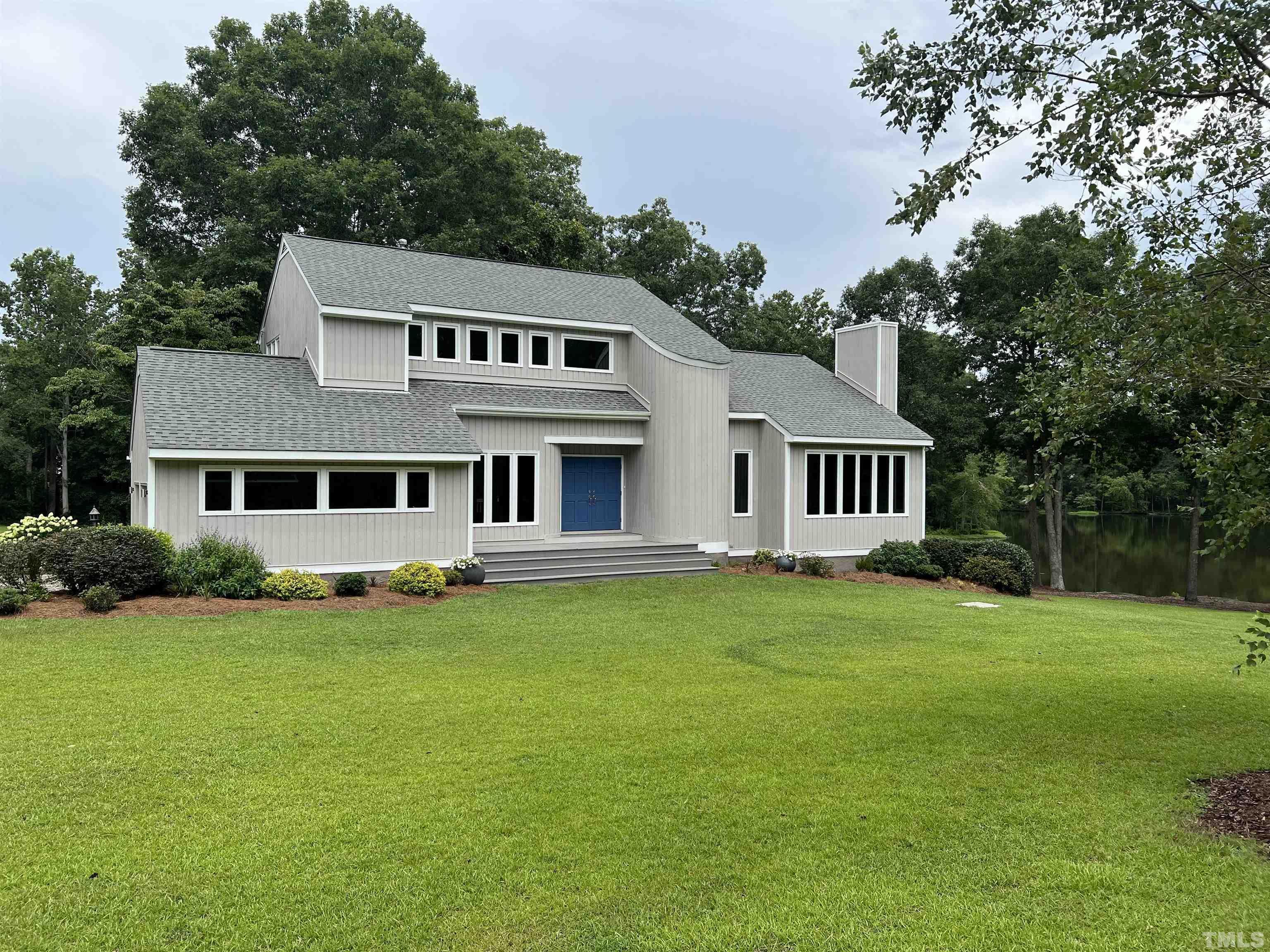 4429 Mitchell Mill Road Wake Forest, NC 27587 - Photo 2 of 35 a house that is sitting in the grass with large trees and plants