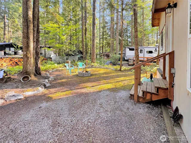 a view of a backyard with table and chairs potted plants and large tree