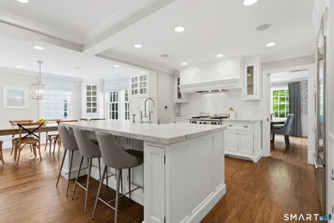 a kitchen with stainless steel appliances granite countertop a table chairs sink and cabinets