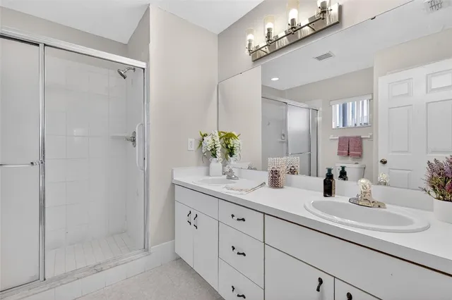 a bathroom with a double vanity sink mirror and shower