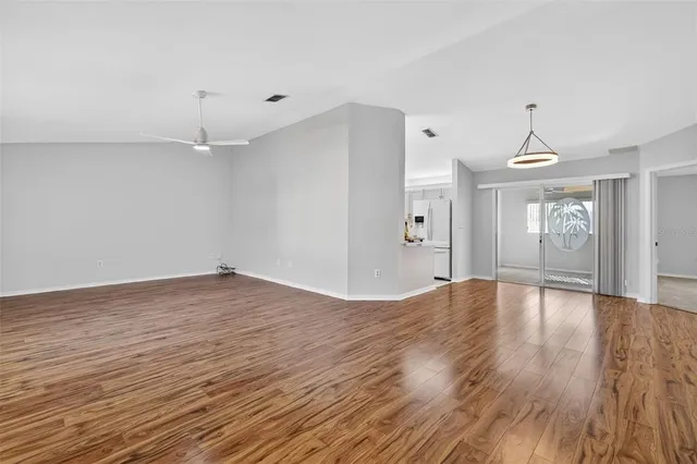 a view of empty room with wooden floor and ceiling fan
