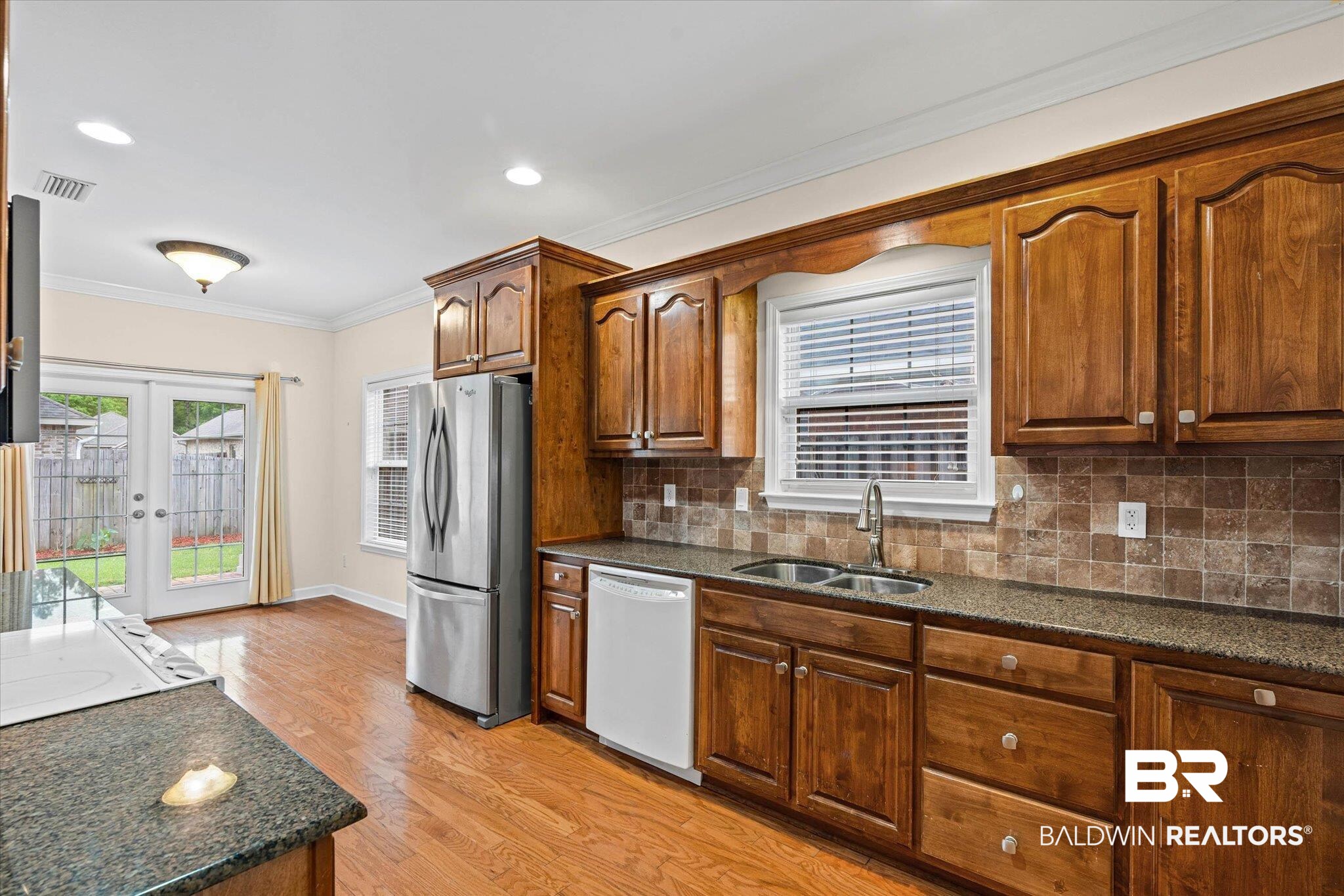 1003 Weatherby Street South Saraland, AL 36571 - Photo 12 of 31 Kitchen featuring ornamental molding, freestanding refrigerator, white dishwasher, dark stone countertops, and light wood finished floors