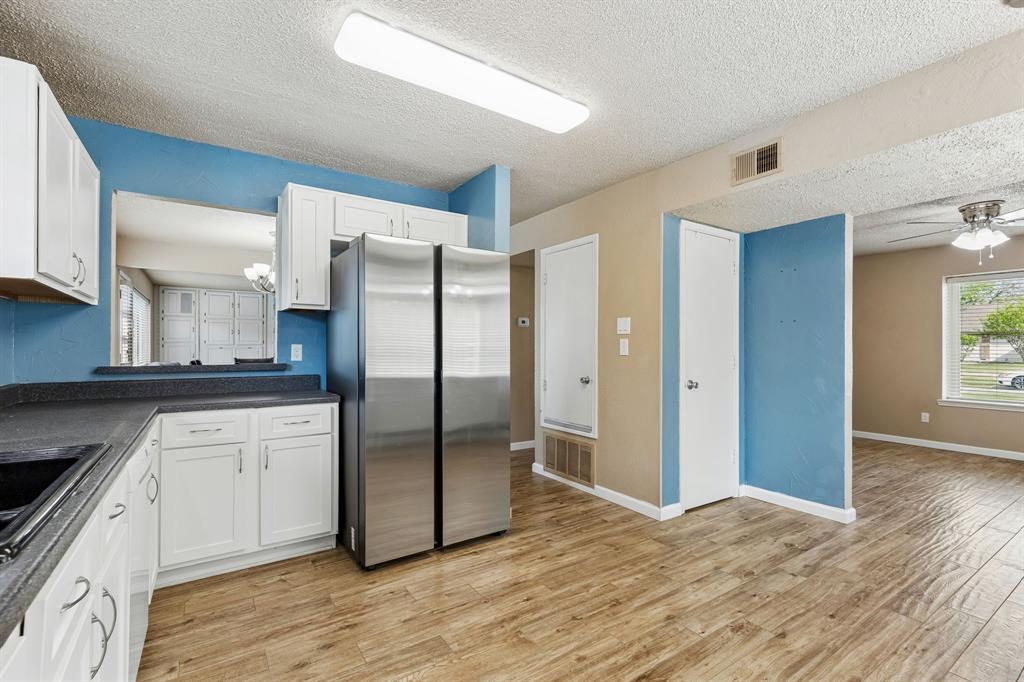 304 Lark Lane Euless, TX 76039 - Photo 12 of 32 Kitchen featuring dark countertops, plenty of natural light, freestanding refrigerator, a ceiling fan, and a textured ceiling
