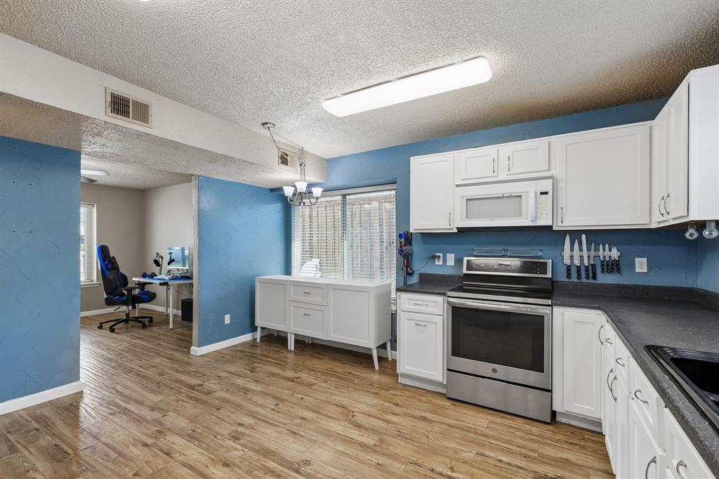 304 Lark Lane Euless, TX 76039 - Photo 14 of 32 Kitchen featuring dark countertops, stainless steel electric range, an office area, a textured ceiling, and white cabinets