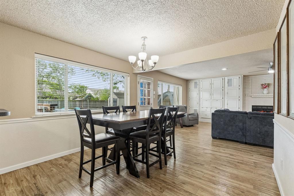 304 Lark Lane Euless, TX 76039 - Photo 15 of 32 Dining space with a textured ceiling, light wood finished floors, a large fireplace, suspended lighting, and a ceiling fan