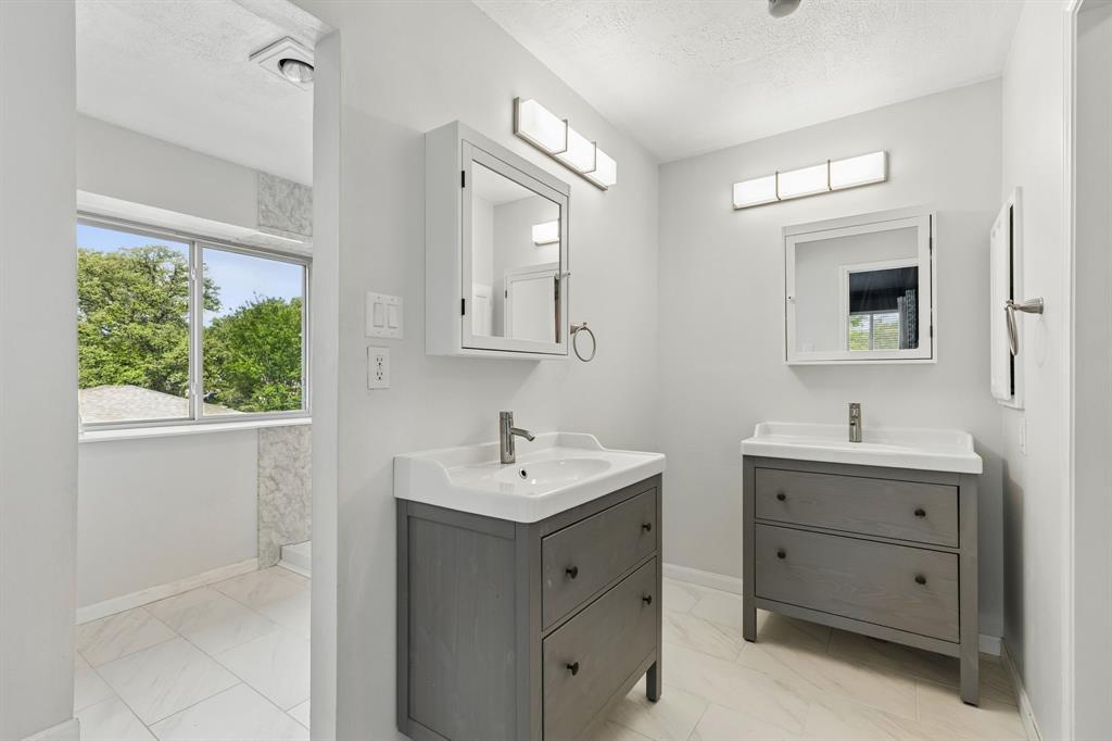 304 Lark Lane Euless, TX 76039 - Photo 18 of 32 Bathroom with two vanities, light marble finish flooring, and a textured ceiling