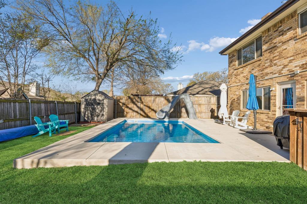 304 Lark Lane Euless, TX 76039 - Photo 30 of 32 View of pool featuring a water slide, a fenced backyard, patio surround, a storage shed, and grilling area
