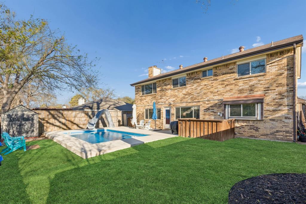 304 Lark Lane Euless, TX 76039 - Photo 32 of 32 Back of property with a storage unit, a chimney, brick siding, and a fenced backyard