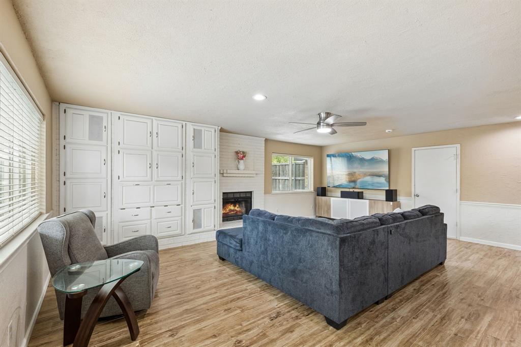 304 Lark Lane Euless, TX 76039 - Photo 8 of 32 Living room with a brick fireplace, ceiling fan, light wood-style floors, a textured ceiling, and recessed lighting
