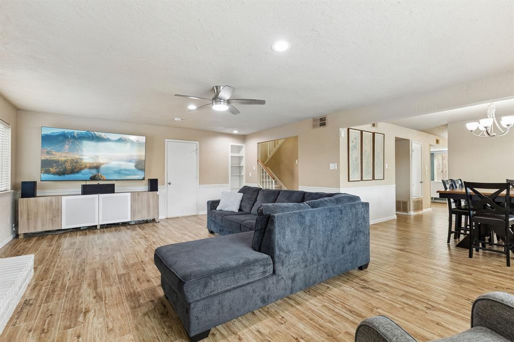 304 Lark Lane Euless, TX 76039 - Photo 10 of 32 Living room featuring light wood-type flooring, a ceiling fan, a textured ceiling, and a chandelier