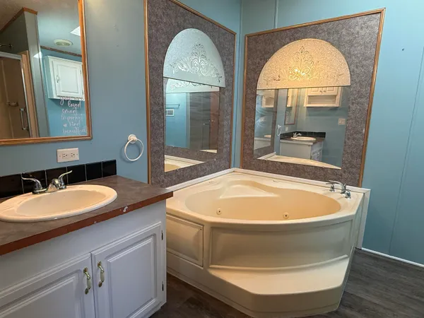 a bathroom with a granite countertop tub a sink and a mirror