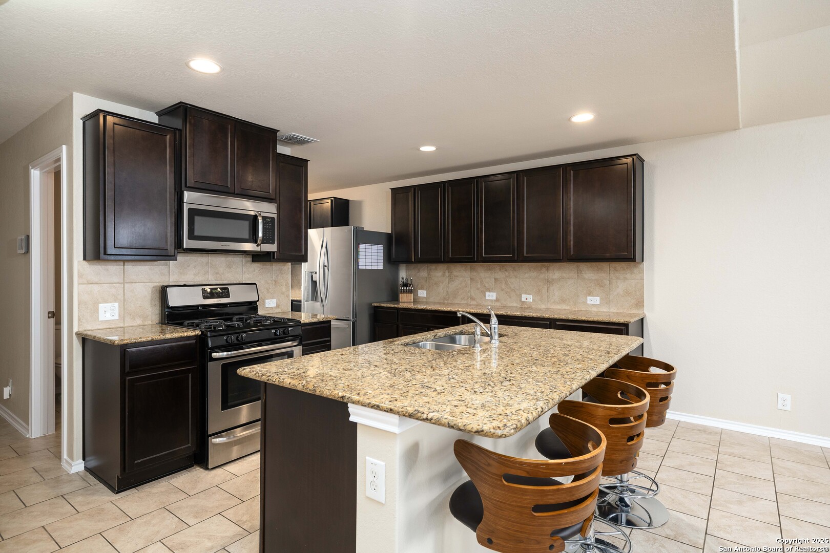 12162 Remilly Way Schertz, TX 78154 - Photo 2 of 18 a kitchen with kitchen island granite countertop cabinets and steel appliances