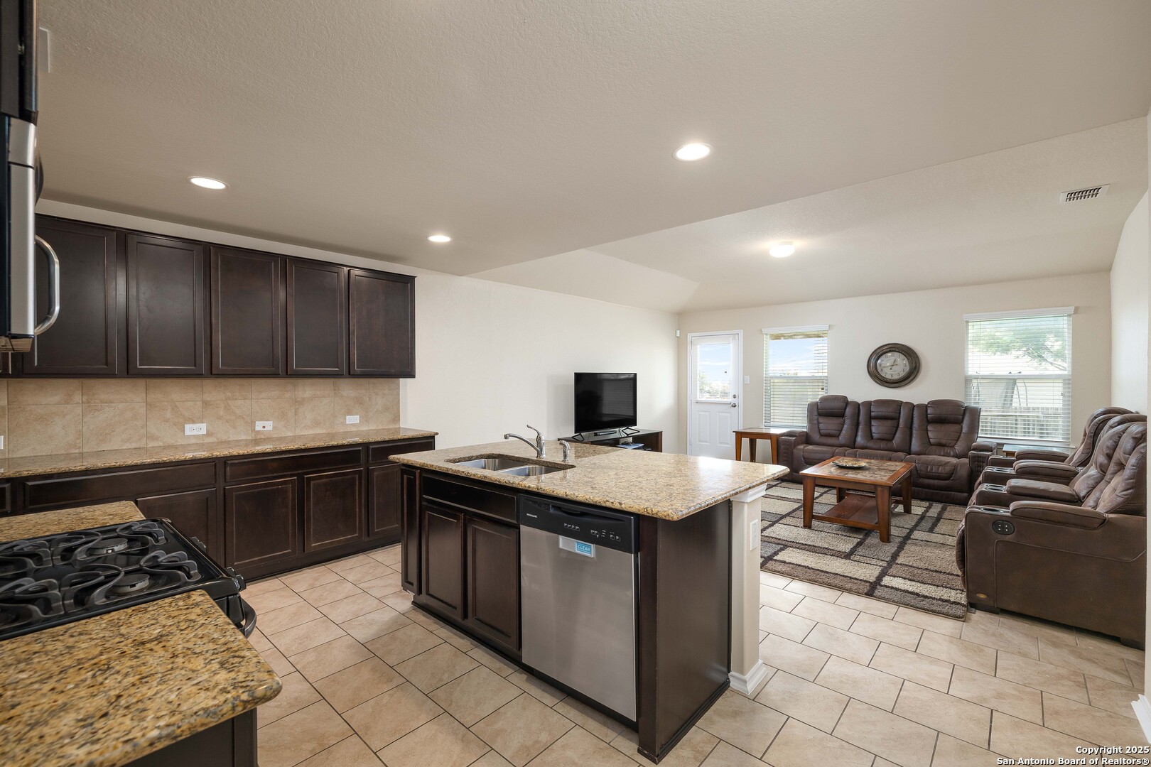 12162 Remilly Way Schertz, TX 78154 - Photo 4 of 18 a kitchen with stainless steel appliances granite countertop a stove top oven a sink dishwasher a dining table and chairs with wooden floor