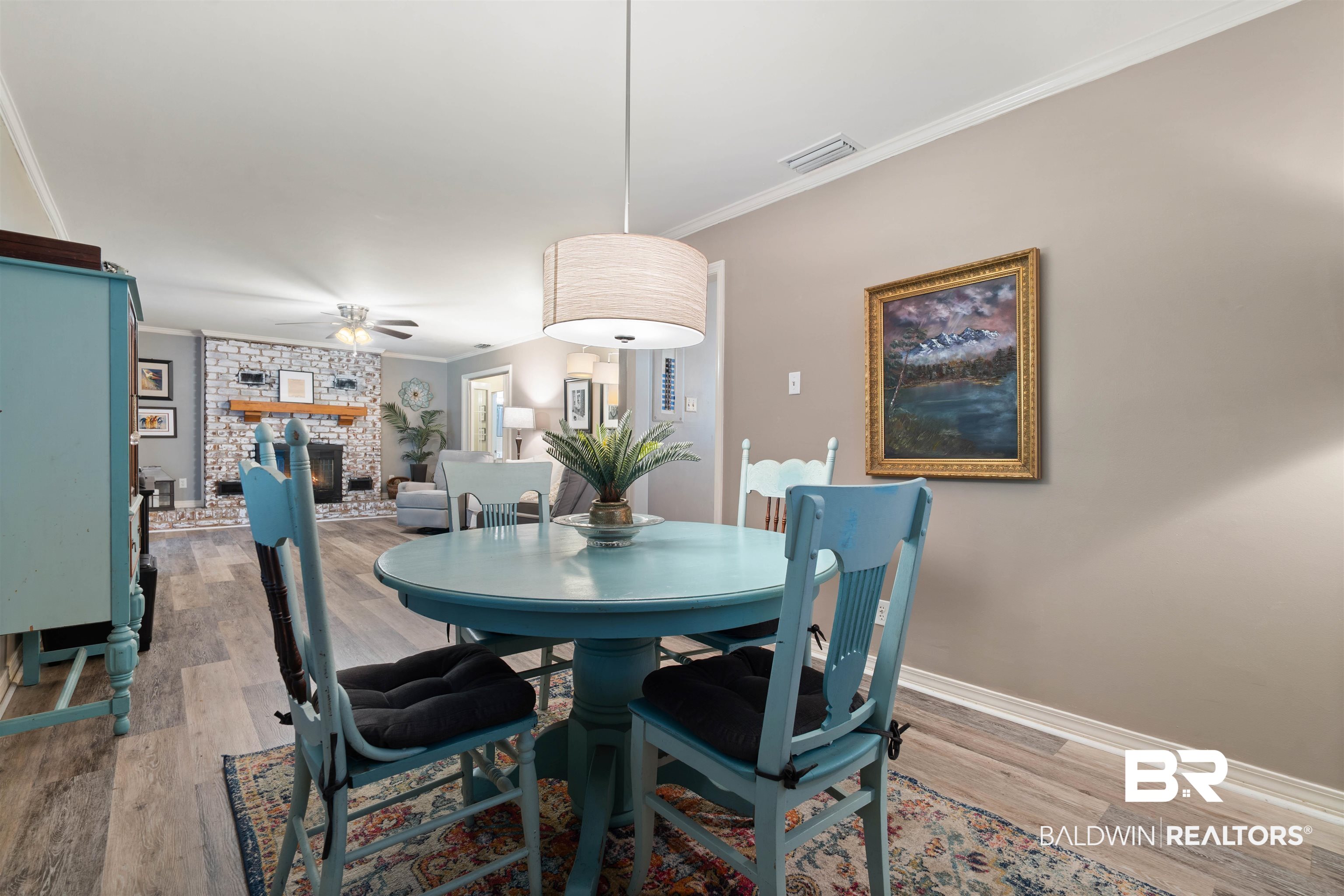 4051 East Canal Circle Mobile, AL 36619 - Photo 16 of 32 Dining area with light hardwood / wood-style floors, ornamental molding, a fireplace, and ceiling fan
