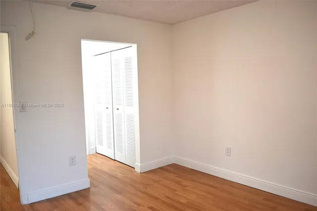 an empty room with wooden floor and closet