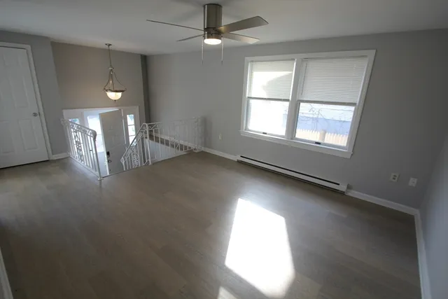 an empty room with windows and ceiling fan