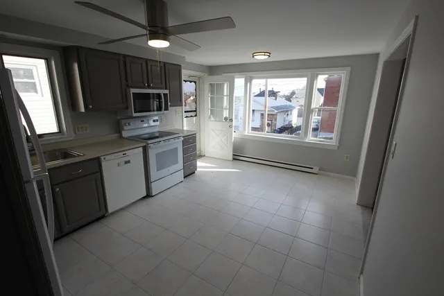 a large kitchen with a stove top oven a sink a counter space and cabinets