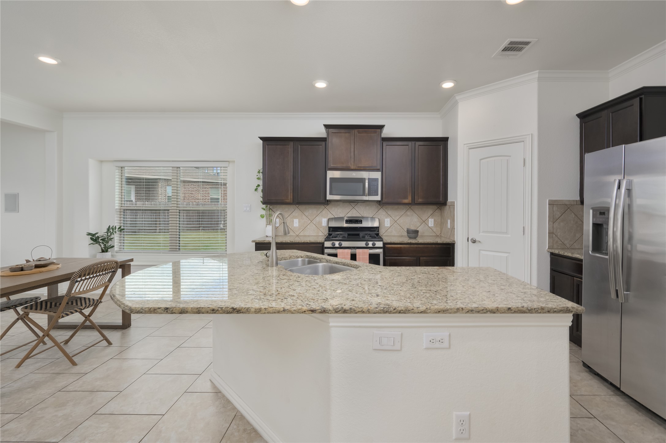 509 Nogales Lane Leander, TX 78641 - Photo 3 of 16 Kitchen featuring light stone countertops, stainless steel appliances, dark wood finish cabinetry, recessed lighting, and tasteful backsplash