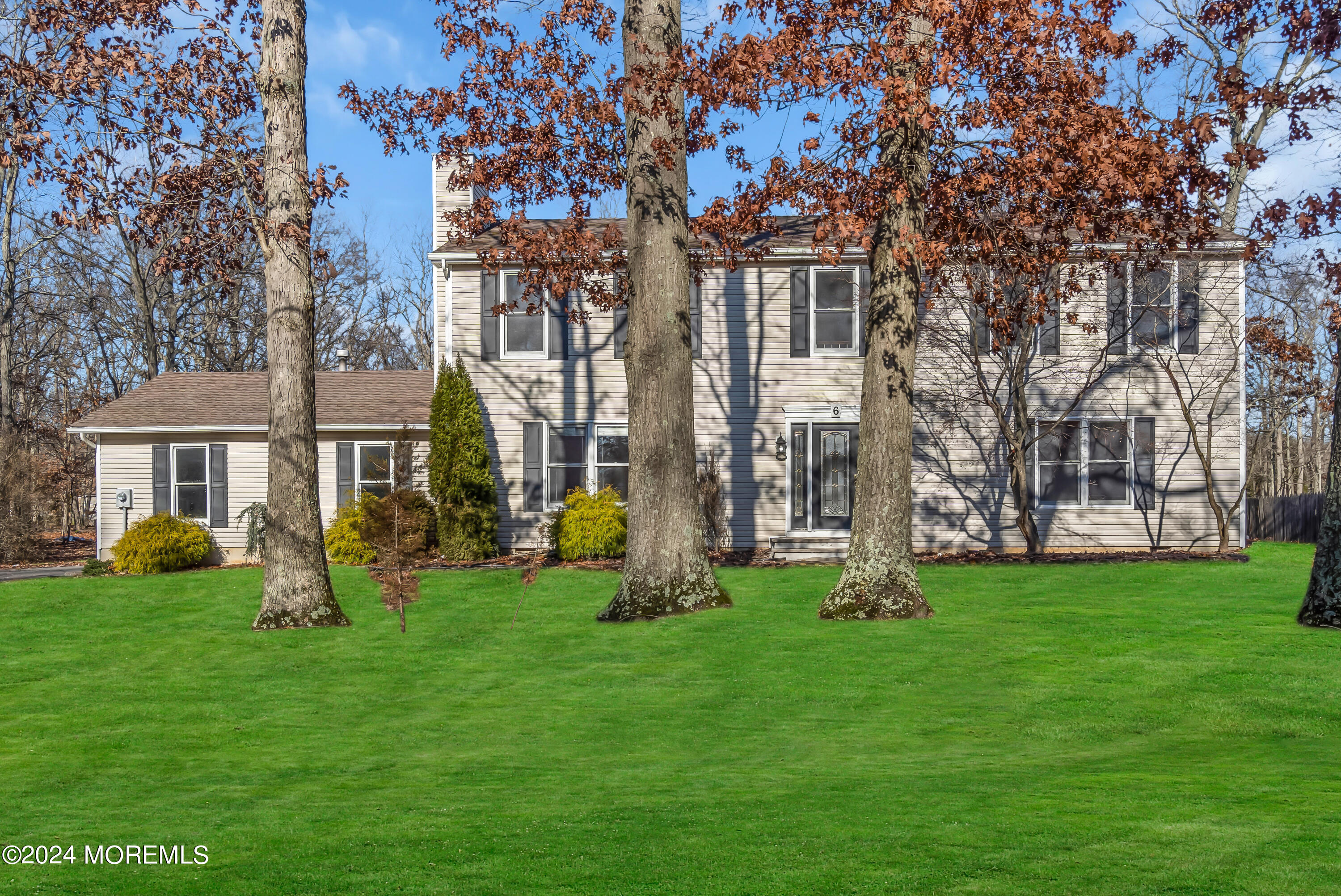a front view of a house with garden and trees