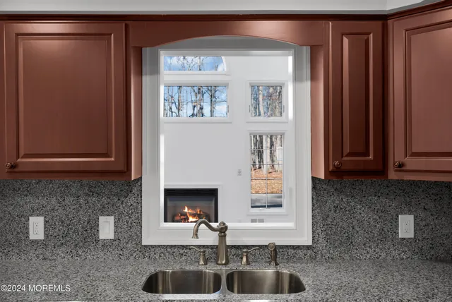 a view of an empty room with wooden floor fireplace and a window