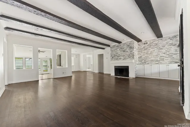 a view of empty room with wooden floor and fireplace
