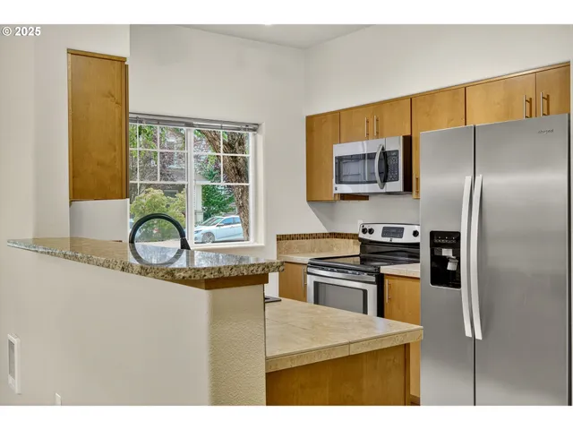 a kitchen with stainless steel appliances granite countertop a refrigerator and a stove top oven