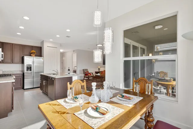 a kitchen with stainless steel appliances kitchen island granite countertop a table chairs and a refrigerator