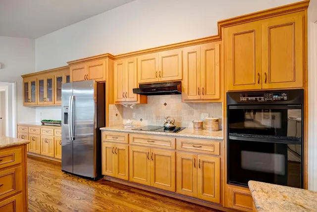 a kitchen with stainless steel appliances granite countertop a refrigerator a stove and a sink with wooden floors
