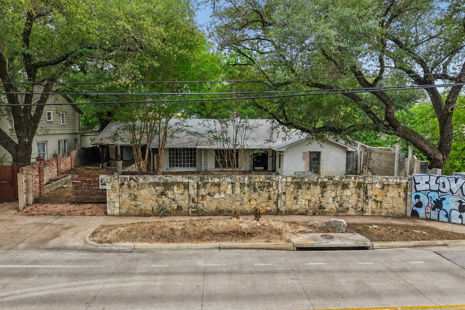 801 East 32nd Street Austin, TX 78705 - Photo 2 of 13 Mature trees frame this charming residence, set back behind a stone wall, offering a private retreat.