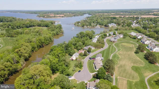 an aerial view of a residential houses with outdoor space and trees all around