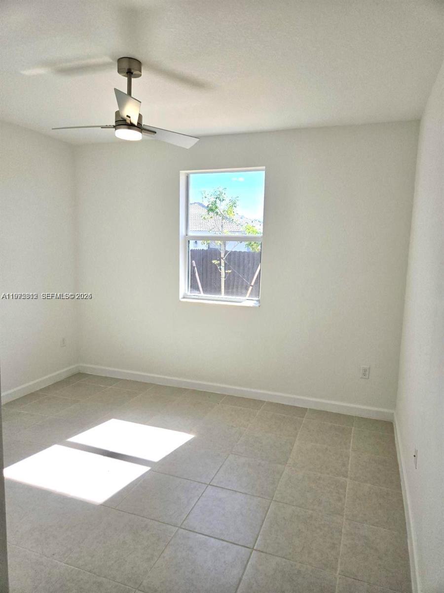 14894 Southwest 163rd Street Miami, FL 33157 - Photo 6 of 15 en empty room with windows and chandelier fan
