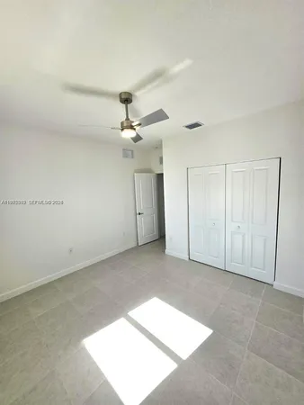 an empty room with a ceiling fan and a window