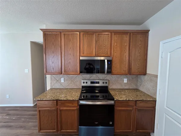 a kitchen with granite countertop wooden cabinets and a stove top oven