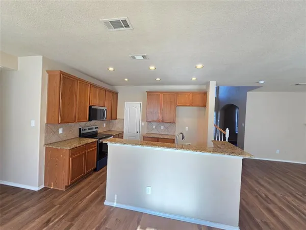 a living room with stainless steel appliances kitchen island granite countertop a stove and a refrigerator