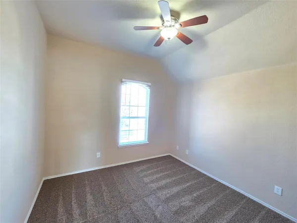 an empty room with a window and ceiling fan