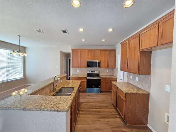 a kitchen with granite countertop a sink stove and refrigerator
